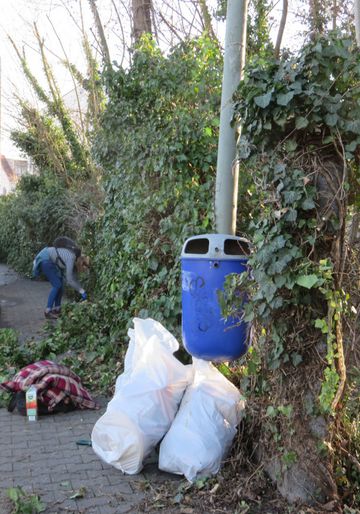 Eine Frau sammelt mit einem Müllbeutel Müll auf