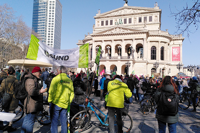 Das Gebäude der Alten Oper Frankfurt im Hintergrund zu sehen, im Vordergrund Ansammlung von Demonstranten. BUND Mitglieder mit aufgestellten BUND Banner.