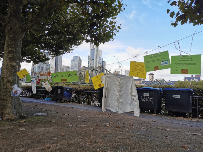 Schnur mit Zetteln und Botschaften zwischen Bäumen vor Frankfurter Skyline zum World Cleanup Day
